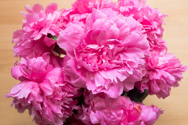 Pivoňka nebo paeony růžové květy ve váze horní pohled. Paeonia "Sarah Bernhardt" kytice na dřevěném pozadí - Fotografie, Obrázek