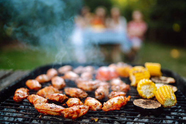 Assorted delicious grilled meat with barbecue grilled vegetables. ompany of people gathered for barbecue in summer garden. Summer, party, adventure, youth, frienship concept - 写真・画像