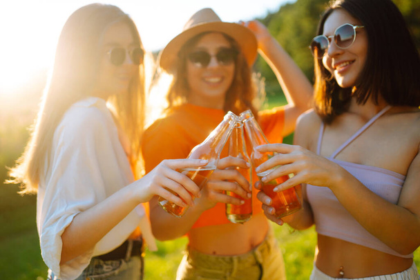 Three young woman is resting at picnic. Girlfriends  enjoy sunny day on beautiful green meadow. Vacation, picnic, friendship or holliday concept. - Foto, imagen