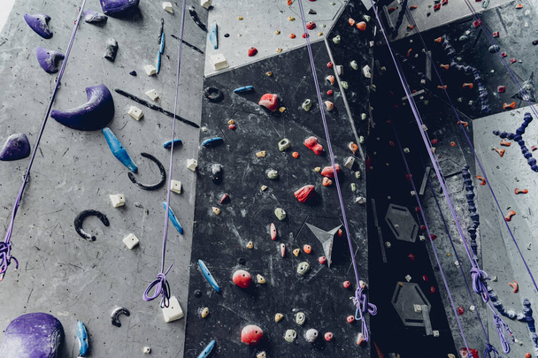 Artificial climbing wall with colorful grips and ropes. - Fotoğraf, Görsel
