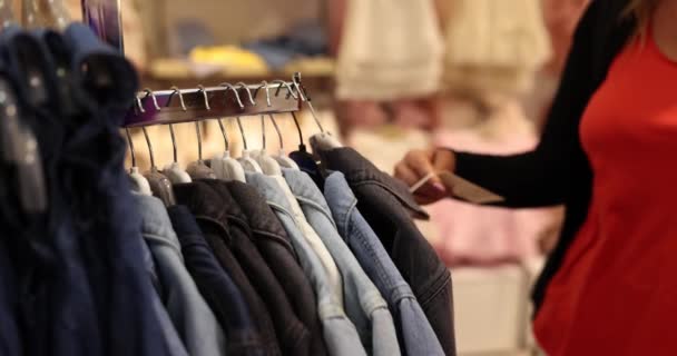 Etykieta w ubraniach wiszących na wieszaku w sklepie odzieżowym. Cenne zniżki i promocje w sklepie odzieżowym - Materiał filmowy, wideo