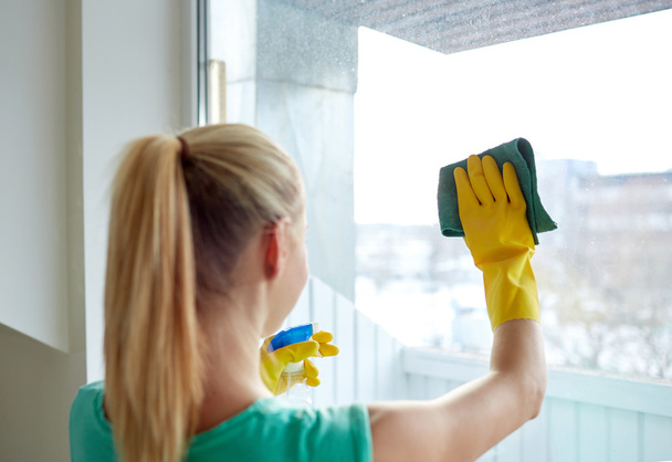 happy woman in gloves cleaning window with rag - Zdjęcie, obraz