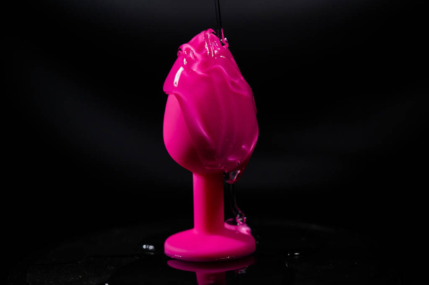 Pink anal plug in intimate lubricant on a black background - Fotó, kép