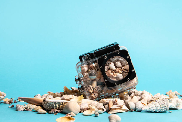 Conchas de mar en caja impermeable de la cámara sobre fondo azul. Concepto de verano. - Foto, imagen