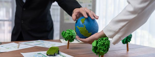 Business people holding paper earth together over office table. Green corporate company implementing eco-friendly policy to reduce CO2 emission and conserve green environment concept. Trailblazing - Фото, зображення