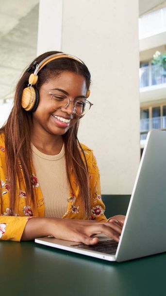 Verticaal van Jonge zwarte Afrikaanse vrouw universitaire student leren online met behulp van laptop computer. Glimlachend meisje kijken webinar of virtueel onderwijs remote class studeren buiten de campus - Foto, afbeelding