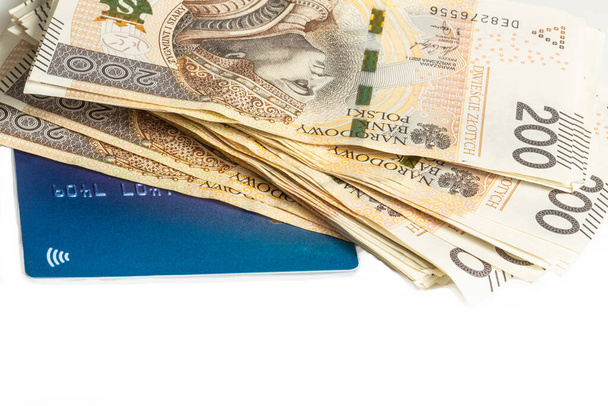 Una gran pila de billetes polacos de 200 zloty y una tarjeta de crédito azul sobre un fondo blanco. Sinónimo de riqueza y abundancia. - Foto, imagen