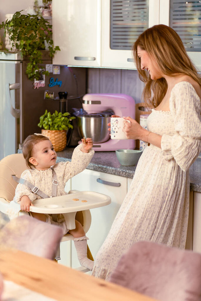 Young mom with her baby girl in the kitchen - Foto, Imagem