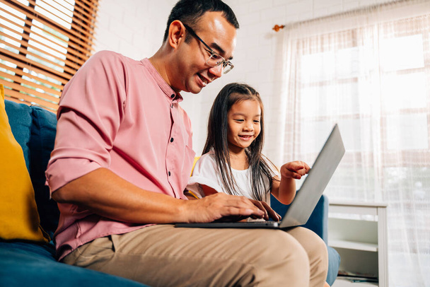 Отец с помощью ноутбука играть с дочерью в гостиной, счастливая семья играть вместе на дому, семья со счастьем - Фото, изображение