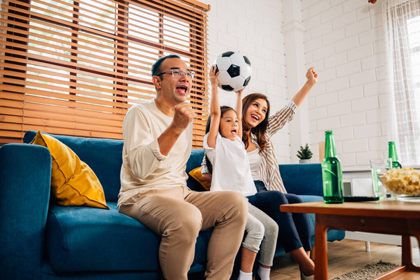 Happy family watching sports match together on television, People cheering and shouting goal with hands up at living room, Father mother and child having fun with activities at home - Foto, Imagem