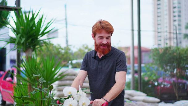 Boldog fiatalember bevásárlókosárral felfedező Aisle a kertészeti boltban. Férfi vásárlói vásárlás a helyi kerti boltban - Fotó, kép
