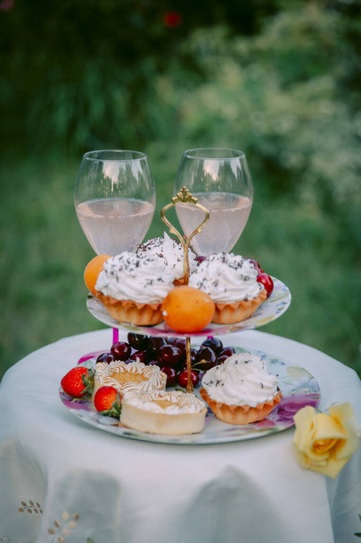 Table with festive treat and white tablecloth in the summer garden - Photo, Image