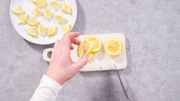 Flat lay. Step by step. Slicing organic lemon wedges on a white plate. - Foto, afbeelding
