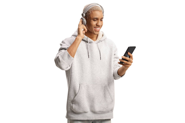 African american young man with headphones listening to music from a mobile phone isolated on white background  - 写真・画像