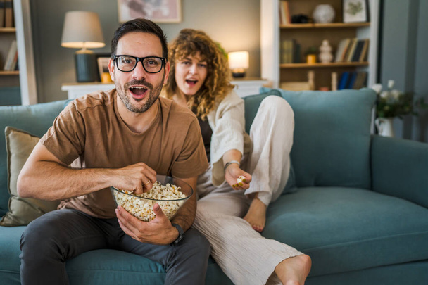 Pár férfi és nő kaukázusi férj és feleség vagy barát és barátnő ülni a kanapén otthon nézni TV film sorozat tál popcorn boldog mosoly kötődés szeretet család koncepció másolás tér - Fotó, kép