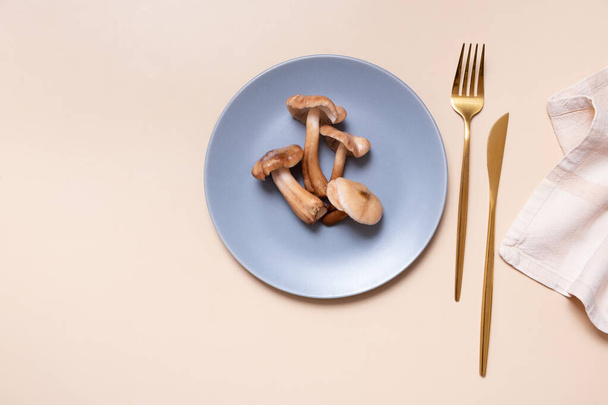 Mushrooms on a plate with cutlery flat lay, top view on beige background. - Photo, Image