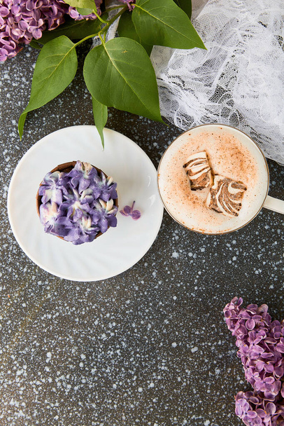 Естетичний оксамитовий фіолетовий торт, чашка кави з розплавленим зефіром зверху серед бузкових квітів. Французький цукор без десерту. Копіювальний простір. - Фото, зображення
