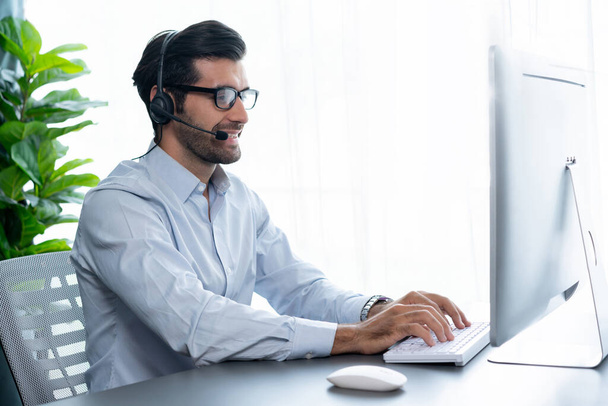 男性コールセンター運営者またはオフィスのデスクに座ってヘッドセットを着用し、顧客サービスサポートを提供するか、販売を行うクライアントとの会話に従事する販売代理店の代表者。フェルヴェント - 写真・画像