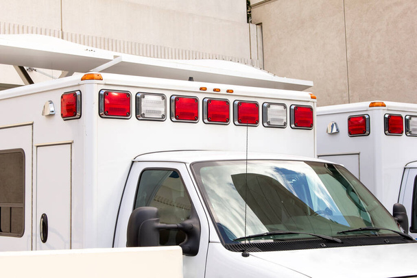 Una vista de un par de ambulancias, estacionadas en la parte trasera de un muelle del hospital. - Foto, imagen