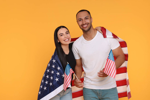 4th of July - Independence Day of USA. Happy couple with American flags on yellow background, space for text - Zdjęcie, obraz