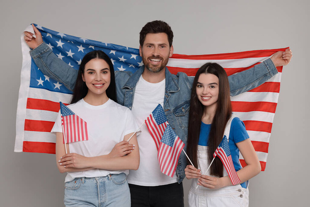 4th of July - Independence Day of USA. Happy family with American flags on grey background - 写真・画像