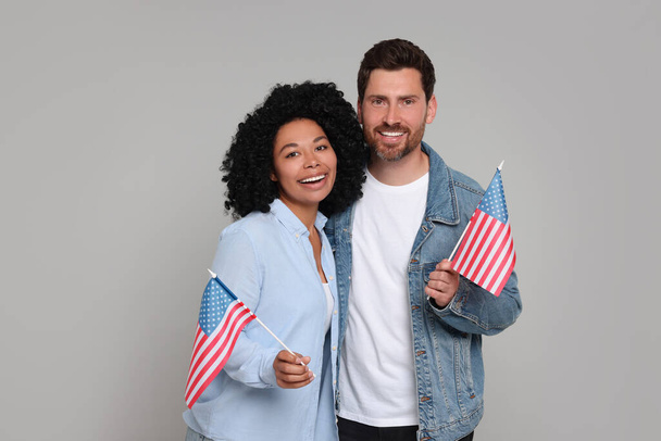 4th of July - Independence Day of USA. Happy couple with American flags on grey background - 写真・画像