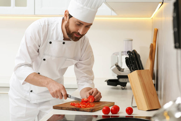 Professional chef cutting tomatoes in stylish kitchen - Foto, afbeelding