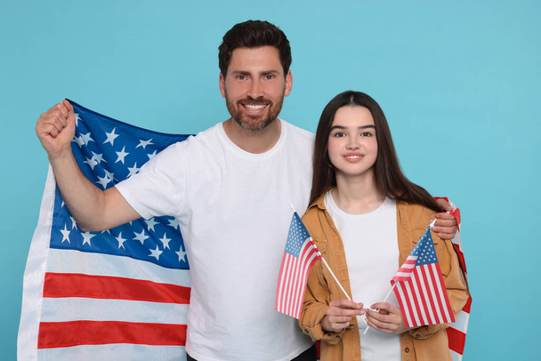 4th of July - Independence Day of USA. Happy man and his daughter with American flags on light blue background - Foto, afbeelding