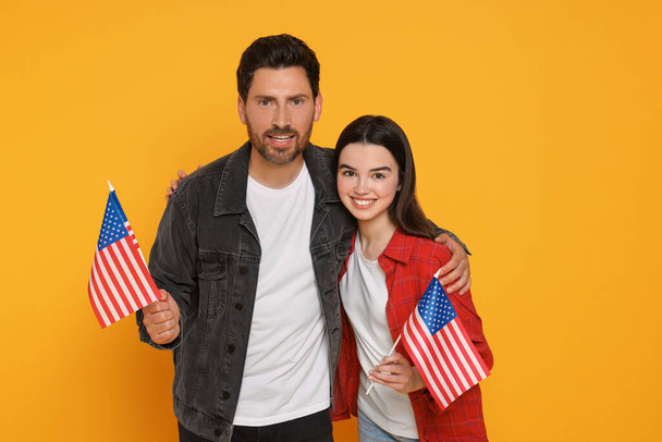 4 juillet - Jour de l'indépendance des Etats-Unis. Homme heureux et sa fille avec des drapeaux américains sur fond jaune - Photo, image