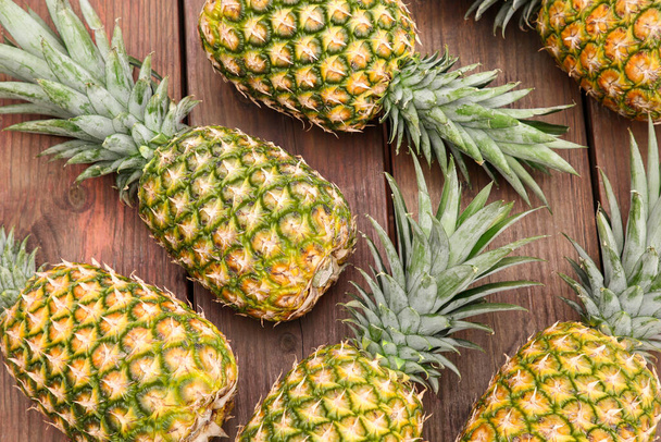 Delicious ripe pineapples on wooden table, flat lay - Photo, image