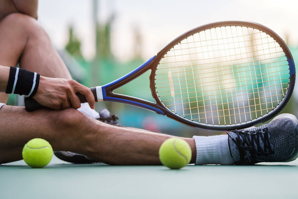 Giocatore di tennis uomo in abiti sportivi seduto sul campo, a riposo dopo la partita o l'allenamento. - Foto, immagini
