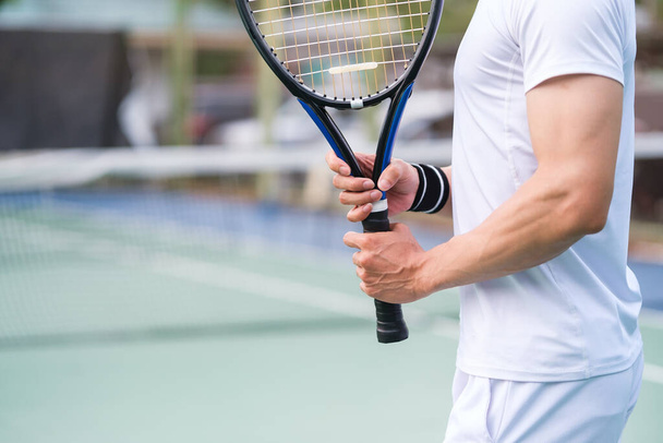Przycięte ujęcie człowieka grającego w tenisa w słoneczny dzień, trzymającego rakietę i piłki - Zdjęcie, obraz
