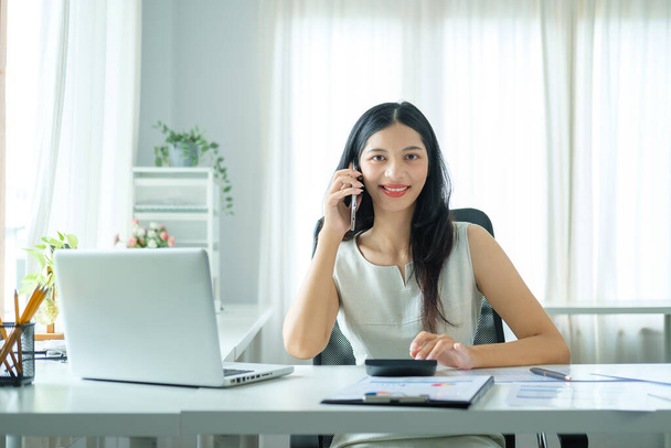 Businesswoman talking on mobile phone while sitting in office. - Foto, imagen