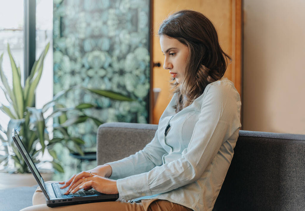 A fêmea usando o laptop para fins de negócios.Uma mulher usando seu laptop em um café, presumivelmente para fins de trabalho - Foto, Imagem