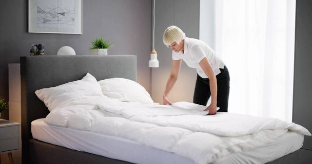 Young Female Housekeeper Changing Bedding In Hotel Room - Foto, Imagen