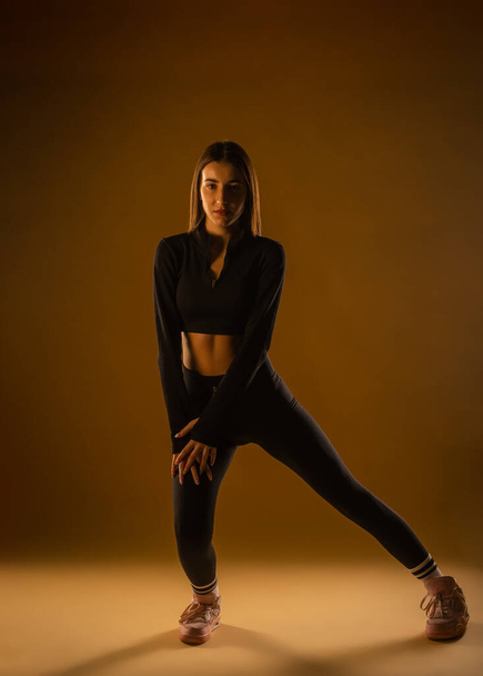 Sports girl in black sports bra and leggings doing exercises in studio - Φωτογραφία, εικόνα