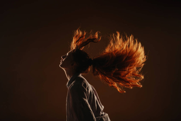 Silhouette of a beautiful girl fliping her hair at the studio while standing - Foto, Imagem