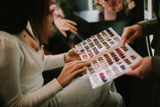 Close up of brunette girl holding the color palette and choosing her hair color from it - Photo, Image