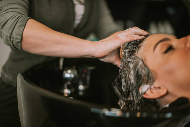 Primer plano de peluquería champú de sus clientes pelo en el lavabo en la peluquería - Foto, imagen