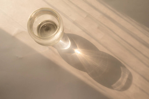 Glass cup on table with reflection of sun rays. minimalistic concept - Foto, Imagen