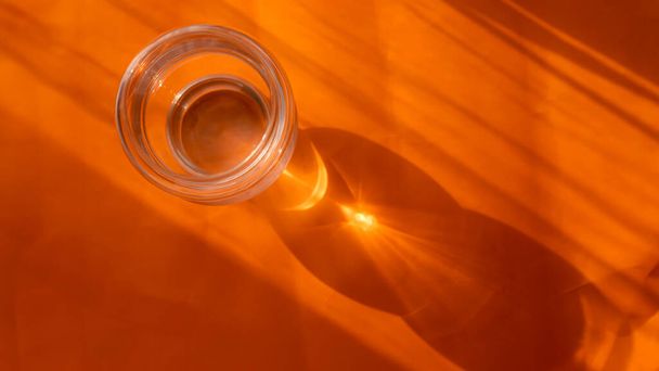Glass cup with with shadow reflection on orange background. minimalistic concept - Foto, imagen