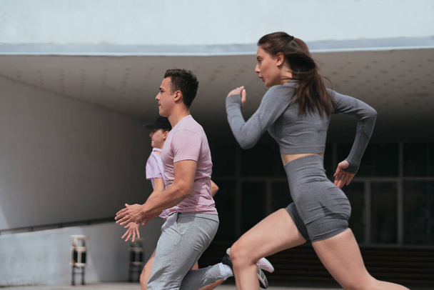 Side view shot of sexy sportspeople sprinting in the city - Photo, Image