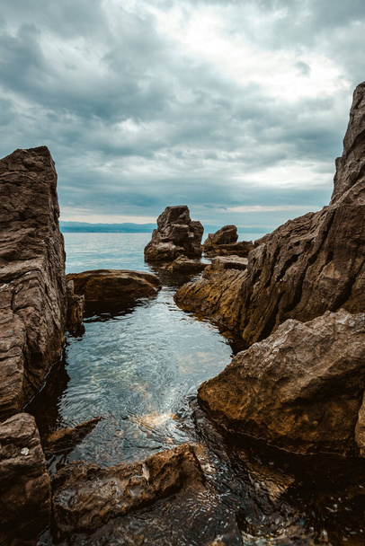 Kvarner gulf of Adriatic sea rocky coastline, large rocks at shoreline in old town of Lovran in Croatia. Selective focus. - Фото, изображение