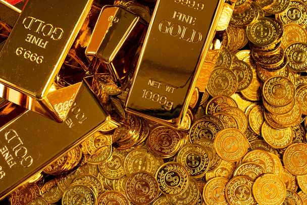 Gouden staven worden geplaatst op een stapel gouden munten - Foto, afbeelding