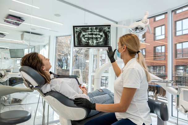 El dentista y el paciente eligen el tratamiento durante la consulta con el equipo médico en odontología. la solución adecuada para el tratamiento de la cavidad oral - Foto, imagen