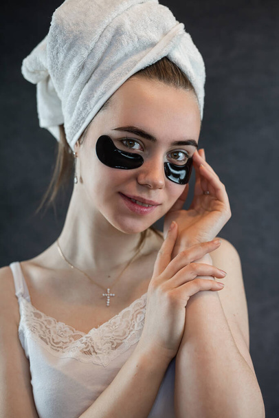 Portrait of young woman with applied black beauty patches isolated on black background. Skin care, rejuvenating - 写真・画像