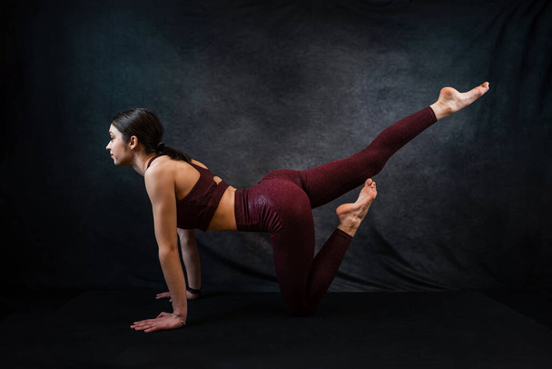 Portret van een mooie vrouw die sportkleding draagt maken geavanceerde yoga of pilates oefening geïsoleerd op zwart. Stretching of yoga thuis - Foto, afbeelding