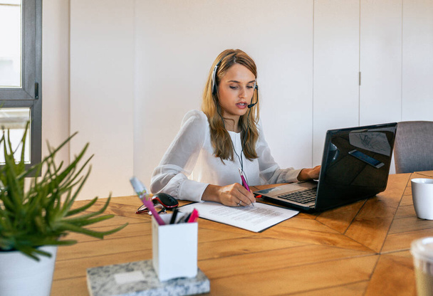 Portrait of young blonde woman with headset in customer help service of coworking. Assistance and support help concept. - Photo, Image