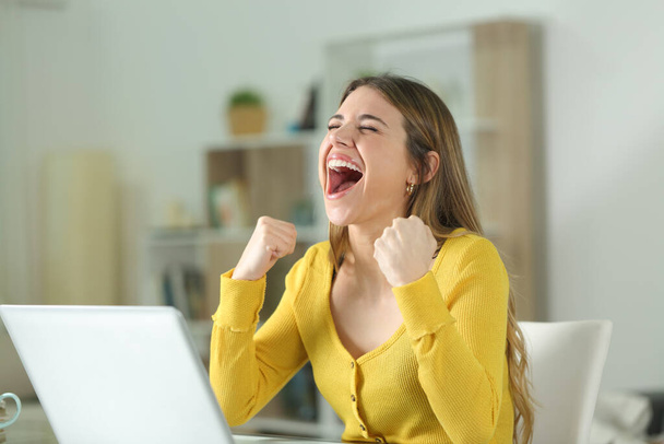 Excited woman with a laptop celebrating sucess at home - Photo, Image