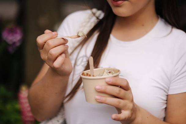 Retrato de una mujer atractiva comiendo helado al aire libre. Descansa después de comprar. Foto de alta calidad - Foto, Imagen